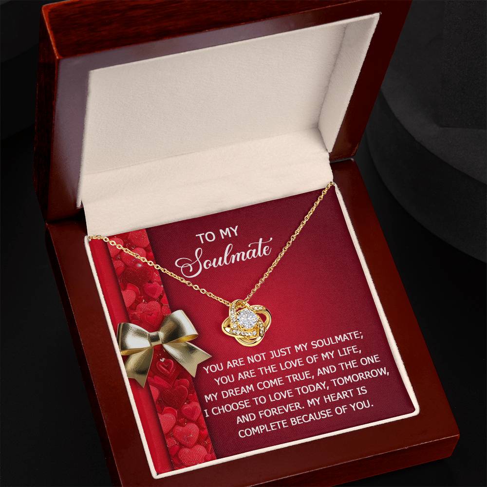 A Soulmate-Because Of You Love Knot Necklace is presented on a red and white card with a romantic message about an unbreakable bond, all elegantly placed in a wooden box.
