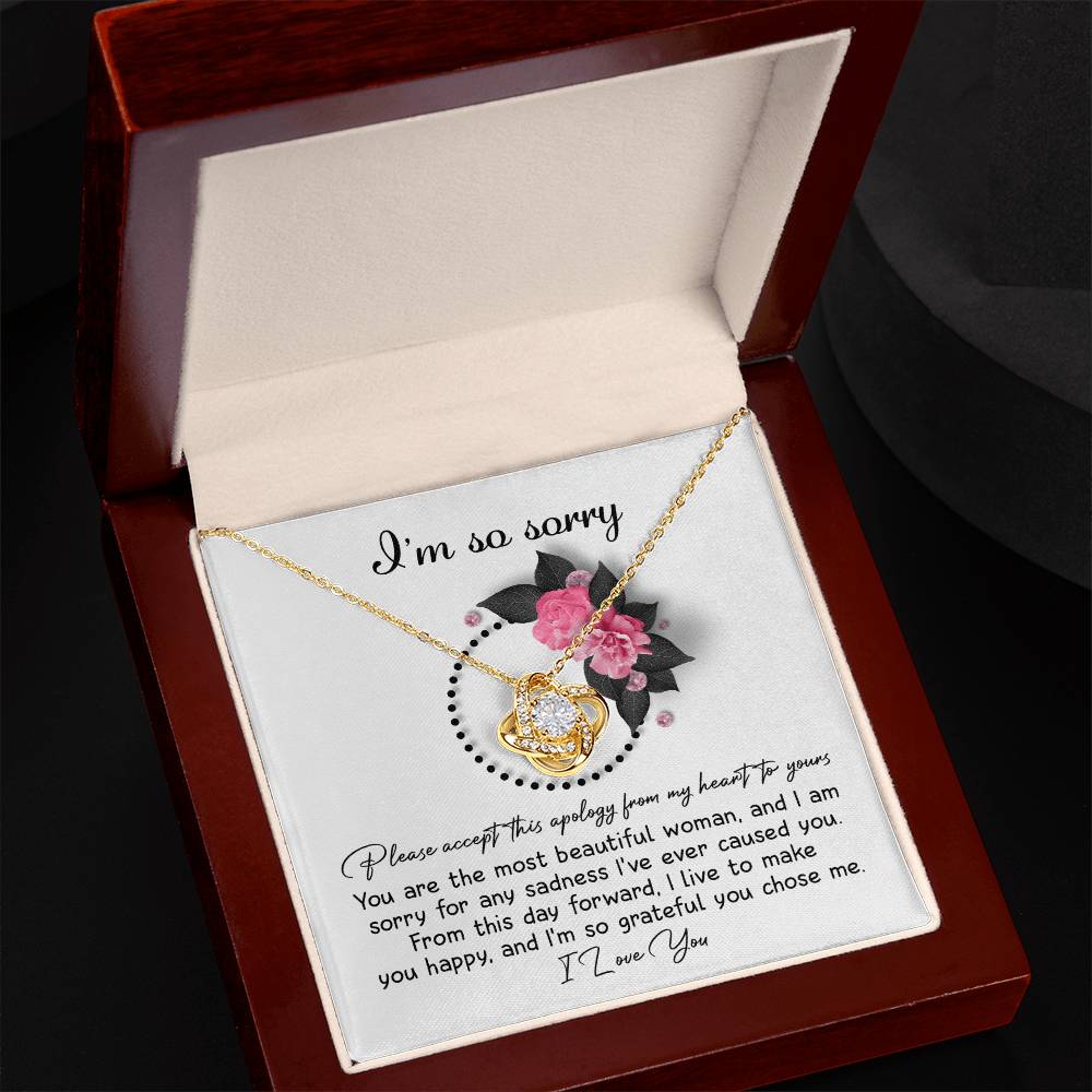 The Sorry-Make You Happy - Love Knot Necklace features a heart-shaped pendant adorned with cubic zirconia crystals, presented in a box decorated with pink flowers and the heartfelt text "I'm so sorry" at the top.