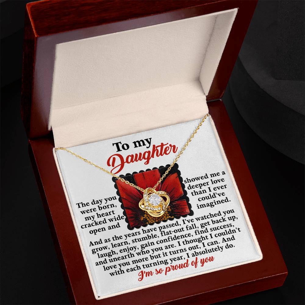 A jewelry gift box contains the "Daughter-A Deeper Love - Love Knot Necklace" adorned with cubic zirconia crystals, accompanied by an engraved message addressed to a daughter expressing love and pride.