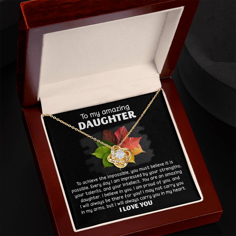 The Daughter-It Is Possible - Love Knot Necklace, featuring a heart-shaped pendant adorned with Premium Cubic Zirconia Crystals, is presented in an open jewelry box. The message reads, "To my amazing daughter, I love you.