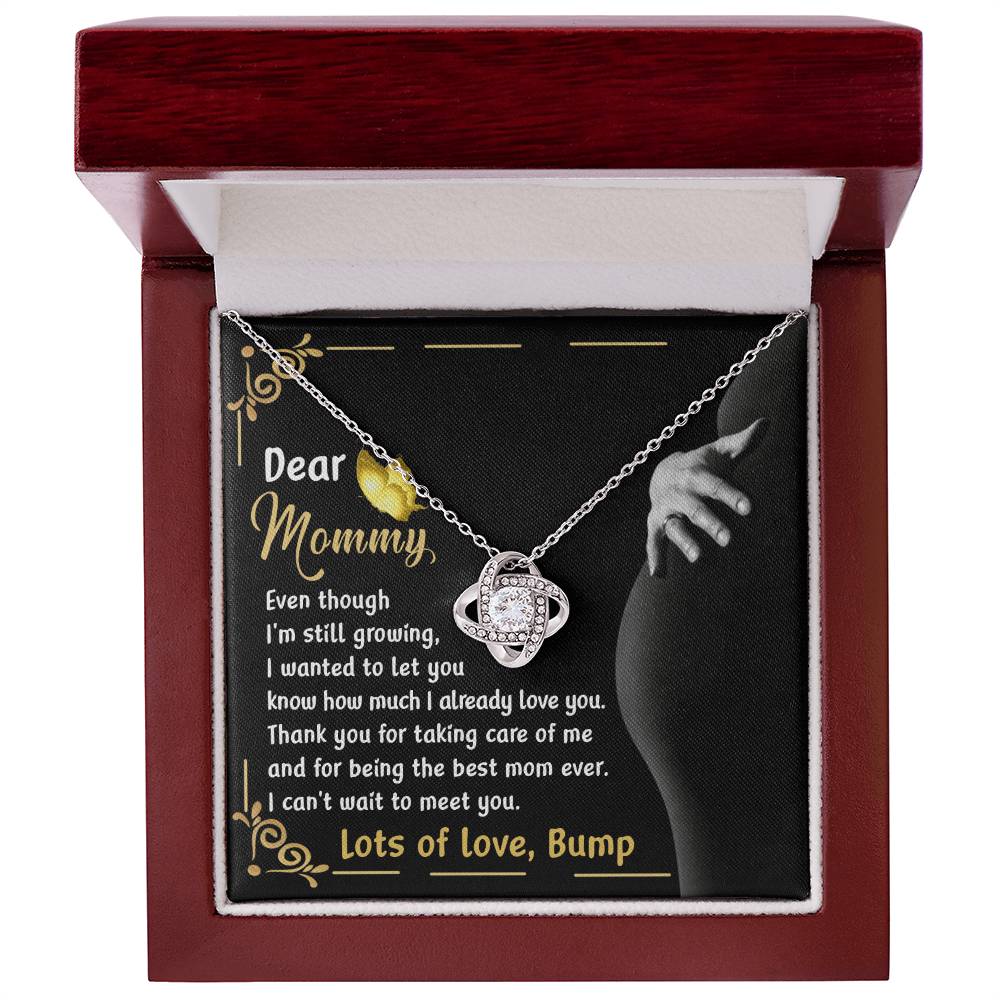 The "To Mama To Be, Best Mom Ever - Love Knot Necklace" comes in a red box adorned with cubic zirconia crystals and is available with either a white gold or yellow gold finish. Inside the box, you’ll find a heartfelt message addressed to "Mommy" from "Bump," expressing love and the anticipation of meeting.