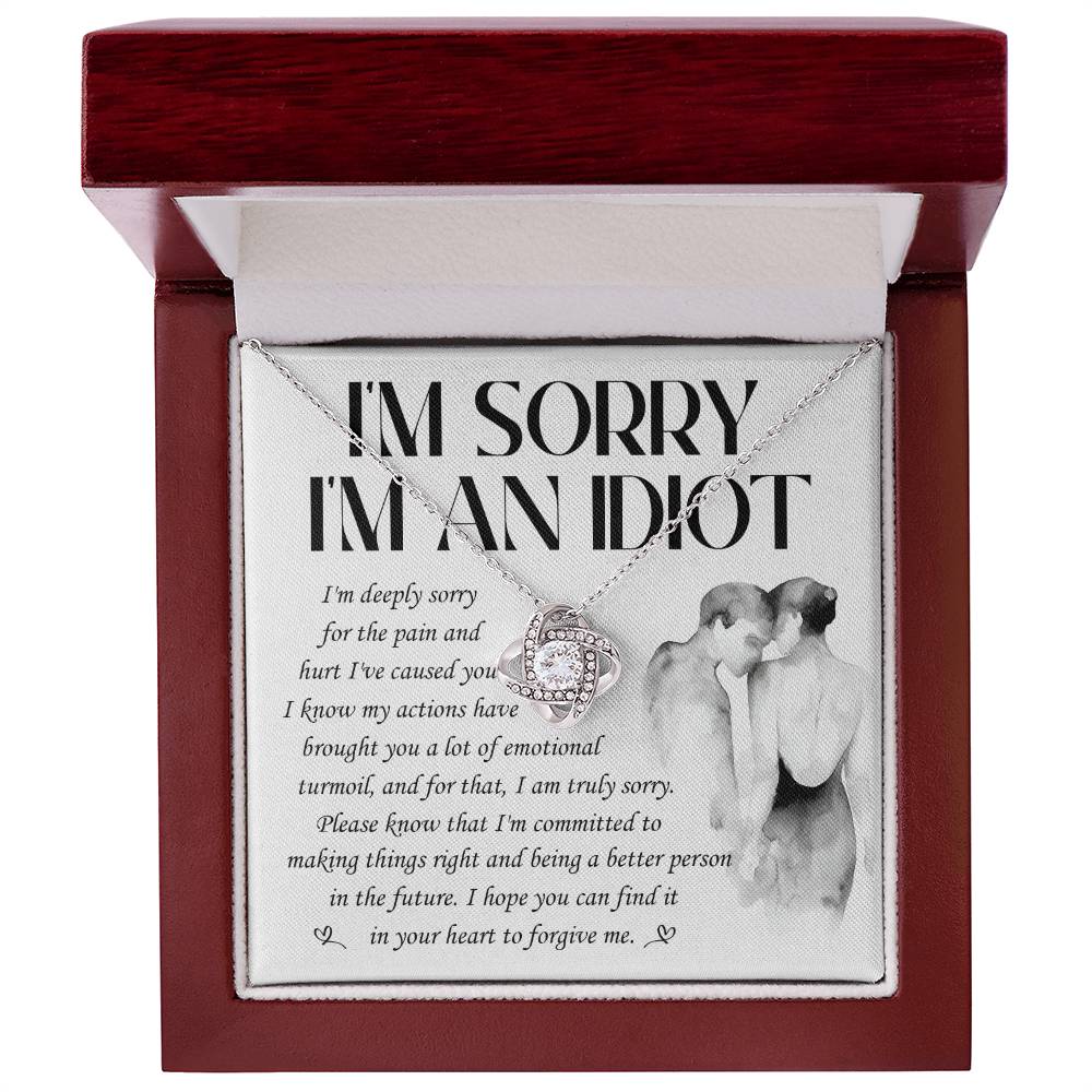The Sorry-Emotional Turmoil - Love Knot Necklace features a heart-shaped pendant adorned with cubic zirconia crystals and comes presented on a card that reads "I'M SORRY I'M AN IDIOT" along with an apology message, accompanied by an illustration of a couple embracing. This elegant necklace is available in either white gold or yellow gold finish.