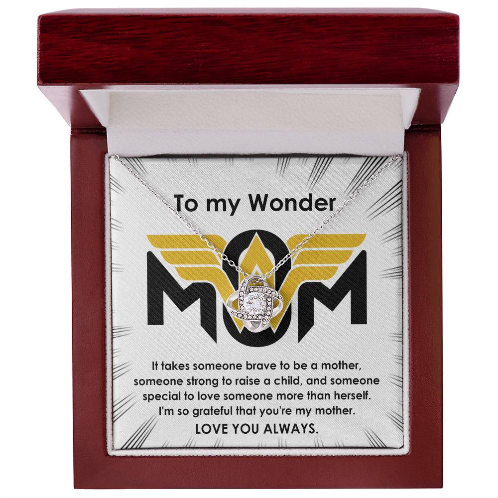 In an open jewelry box, the "To Mom, More Than Herself - Love Knot Necklace" features a stunning design with cubic zirconia crystals. The word "MOM" is prominently displayed along with a heartfelt message of gratitude and admiration for a mother.
