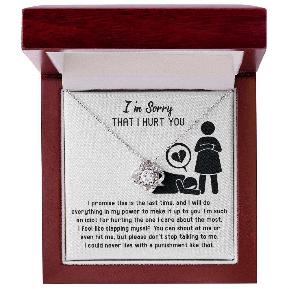 A Sorry-Stop Talking - Love Knot Necklace featuring a heart-shaped pendant adorned with cubic zirconia crystals is displayed in an open jewelry box. The inside lid reads "I'm Sorry THAT I HURT YOU" with an illustration of a person kneeling next to a heart symbol. Text apologizing is visible, making it the perfect personalized gift.
