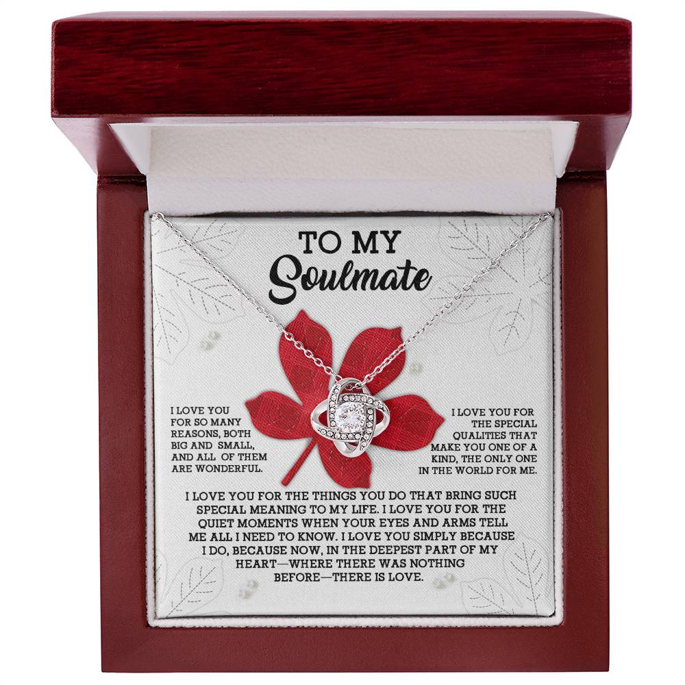A "Soulmate-There Is Love - Love Knot Necklace" with a heart-shaped pendant is displayed in an open red box. Adorned with cubic zirconia crystals and a gold finish, the inscription reads, "To My Soulmate," followed by a heartfelt message about love and appreciation.