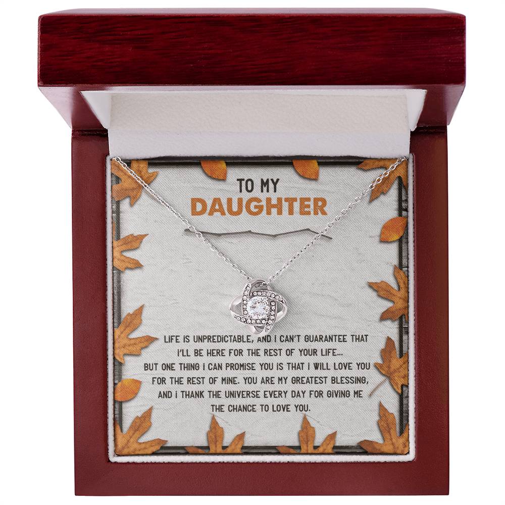 The Daughter-My Greatest Blessing - Love Knot Necklace features a heart-shaped pendant presented in a wooden box. The inside lid of the box is embellished with cubic zirconia crystals, encircling a touching message that reads "To My Daughter" amidst a delicate leaf design, signifying the unbreakable bond you share.