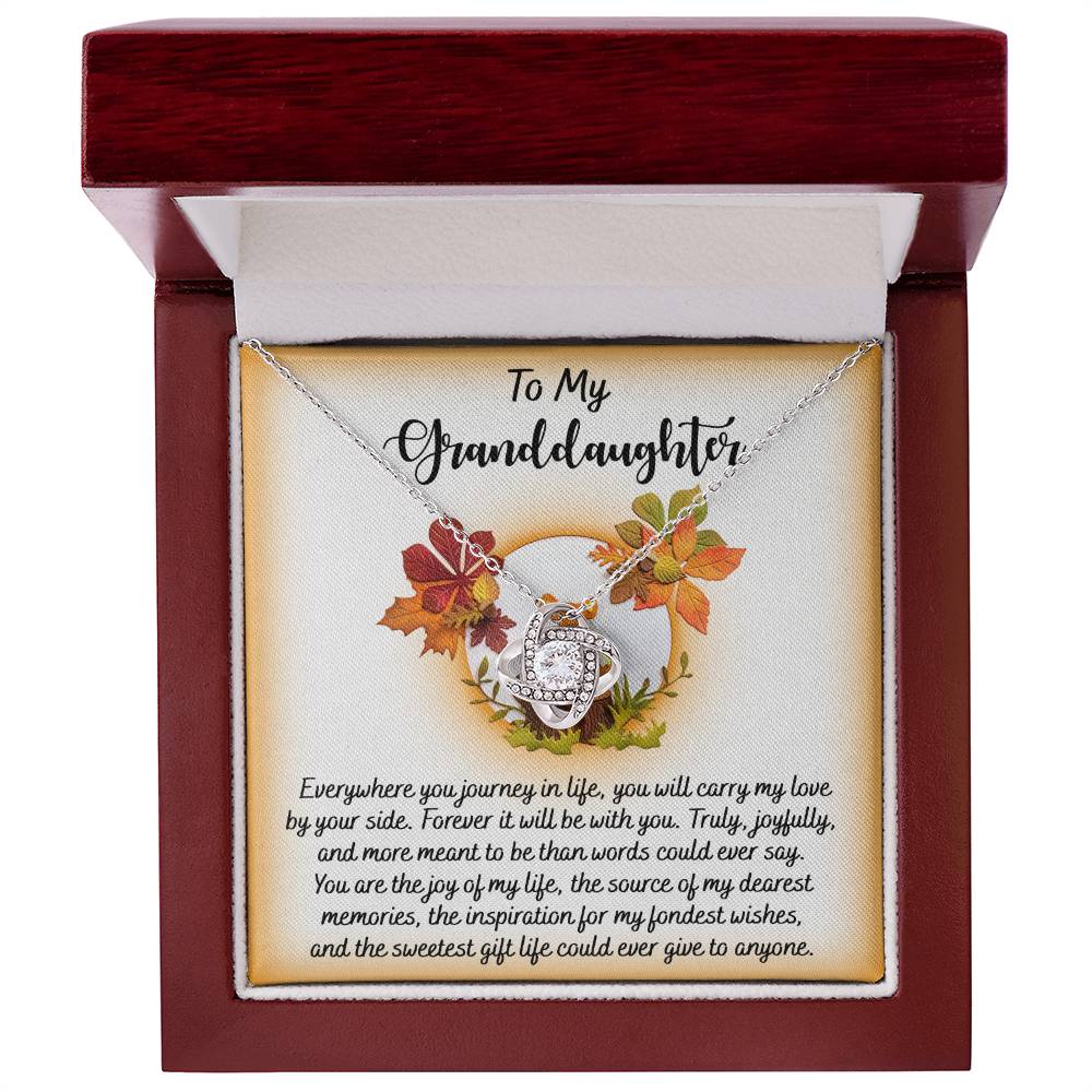 A Granddaughter-By Your Side - Love Knot Necklace crafted in white gold, featuring a circular pendant adorned with an autumn leaf design and sparkling cubic zirconia, presented in a box with a heartfelt message for a granddaughter.