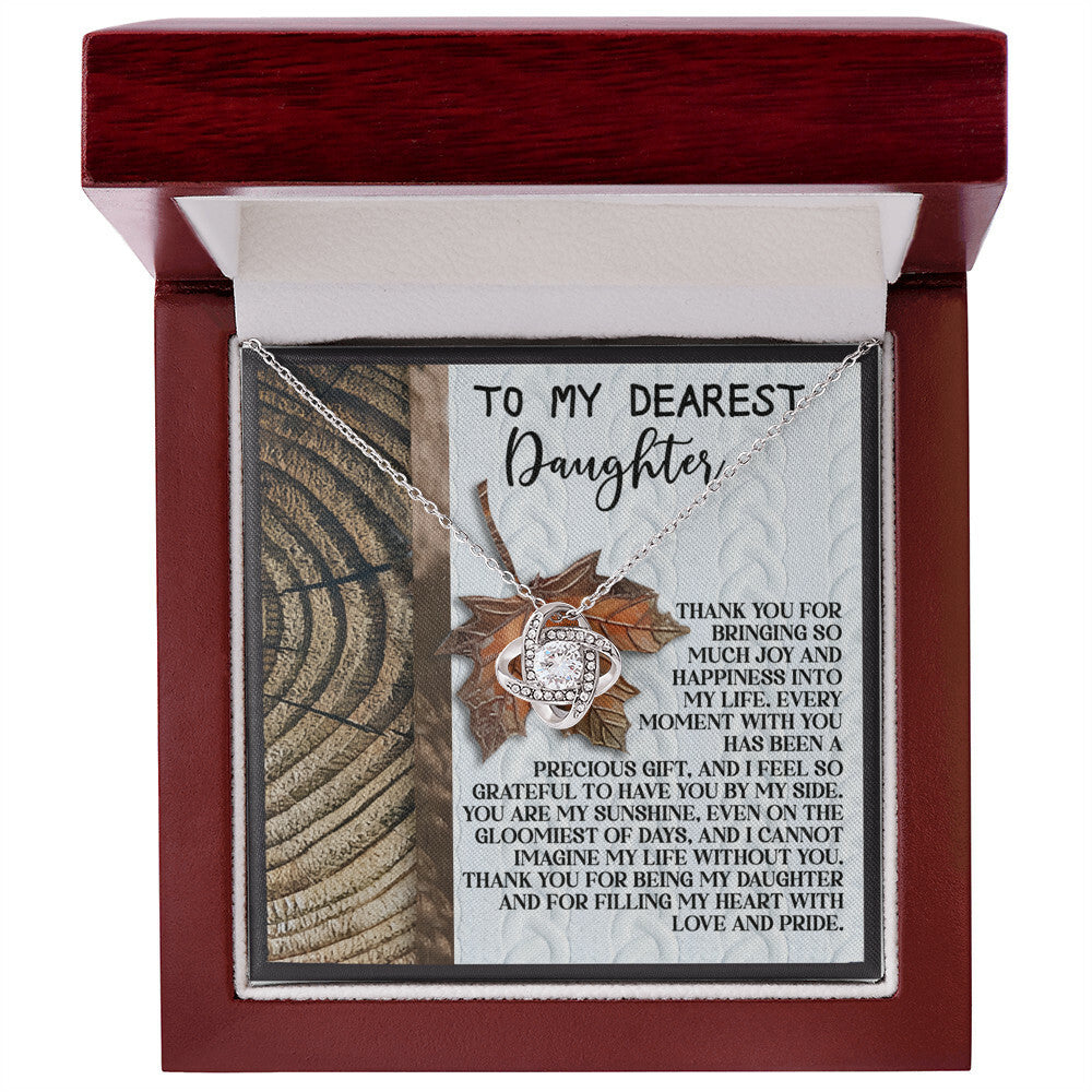 The Daughter-Love And Pride - Love Knot Necklace comes nestled in a charming wooden box and is adorned with shimmering cubic zirconia crystals. The inscribed message starts with "To my dearest daughter" and gracefully concludes with "and for filling my heart with love and joy." This personalized gift beautifully expresses heartfelt emotions.