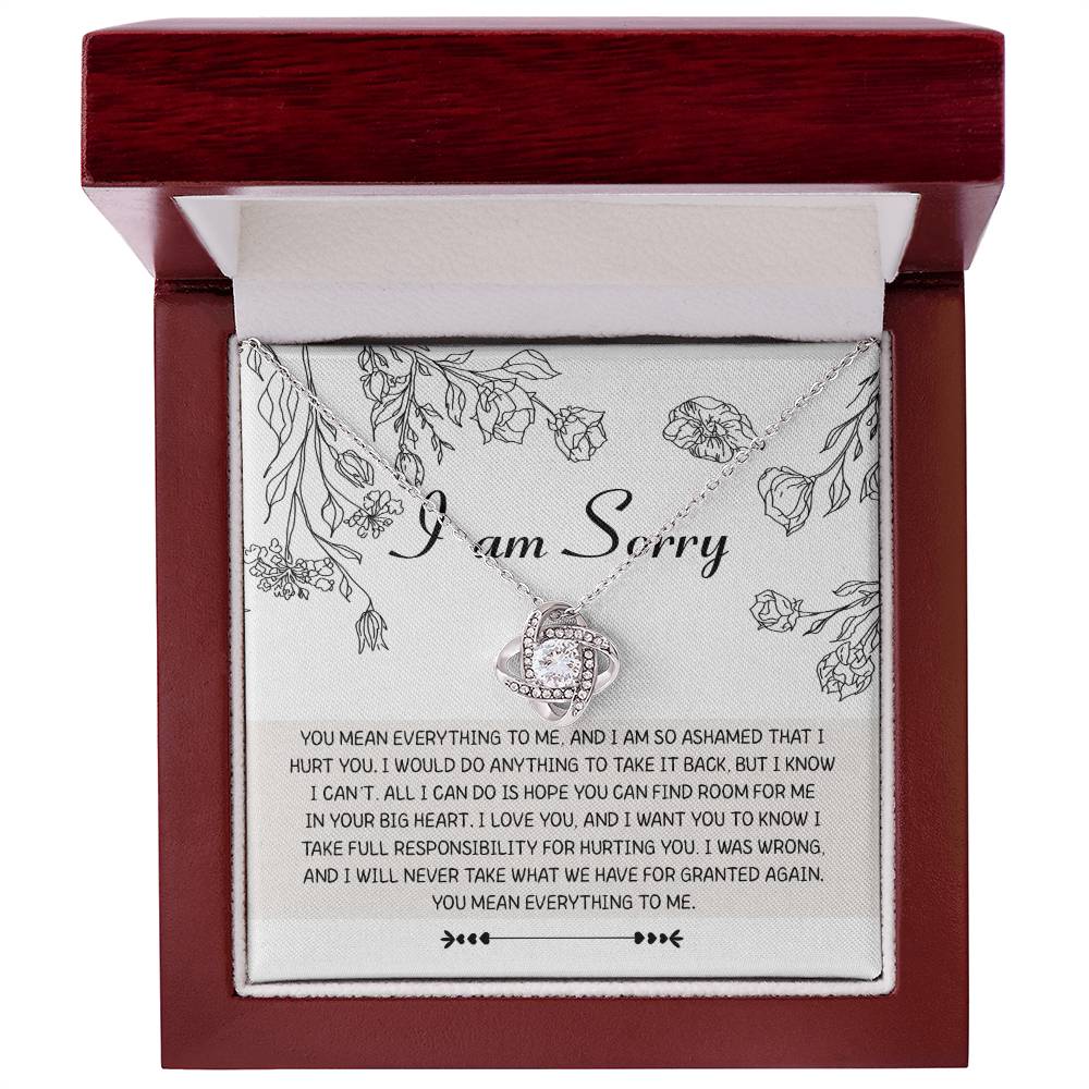 Introducing the "Sorry-Your Big Heart - Love Knot Necklace": This exquisite white gold necklace showcases an elegant intertwined heart design, adorned with shimmering cubic zirconia crystals. It comes complete with a heartfelt card that reads, "I am Sorry," followed by an apologetic message. The entire set is beautifully presented in a floral-printed box.