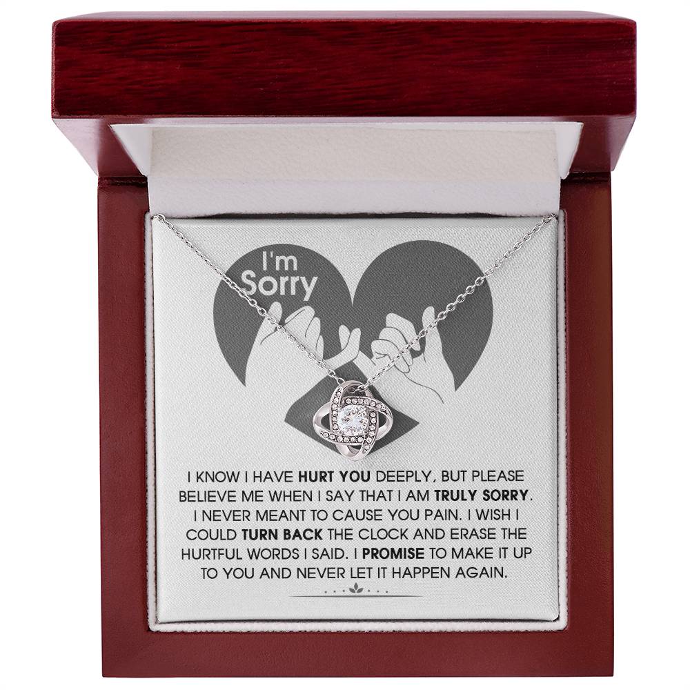 The Sorry-Hurtful Words Love Knot Necklace is displayed on a card featuring an illustration of a heart and hands. The card conveys an apology message that expresses deep regret and a promise to make amends. This personalized gift is adorned with cubic zirconia, symbolizing the depth of sincerity and commitment.