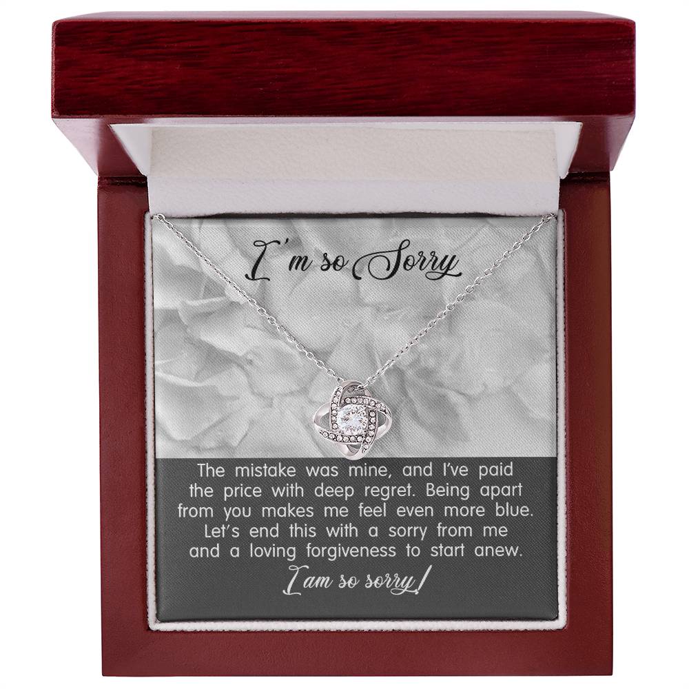 A Sorry-With Deep Regret - Love Knot Necklace with a white gold finish and a pendant on a card that says "I'm so Sorry." The card contains an apology message expressing regret and a plea for forgiveness.