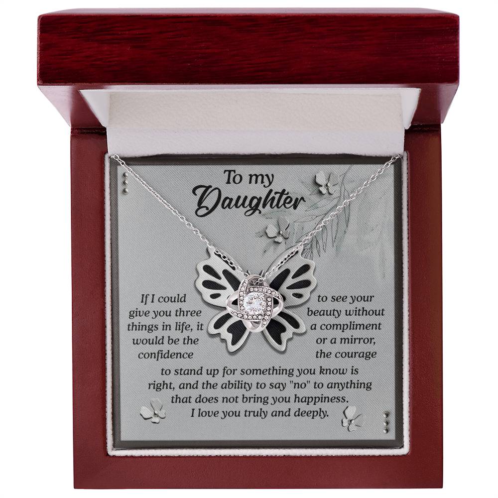 The Daughter-See Your Beauty - Love Knot Necklace, featuring a gold-finish butterfly pendant adorned with premium cubic zirconia crystals, is elegantly displayed in an open wooden box with an inspirational message for a daughter on the inside lid.