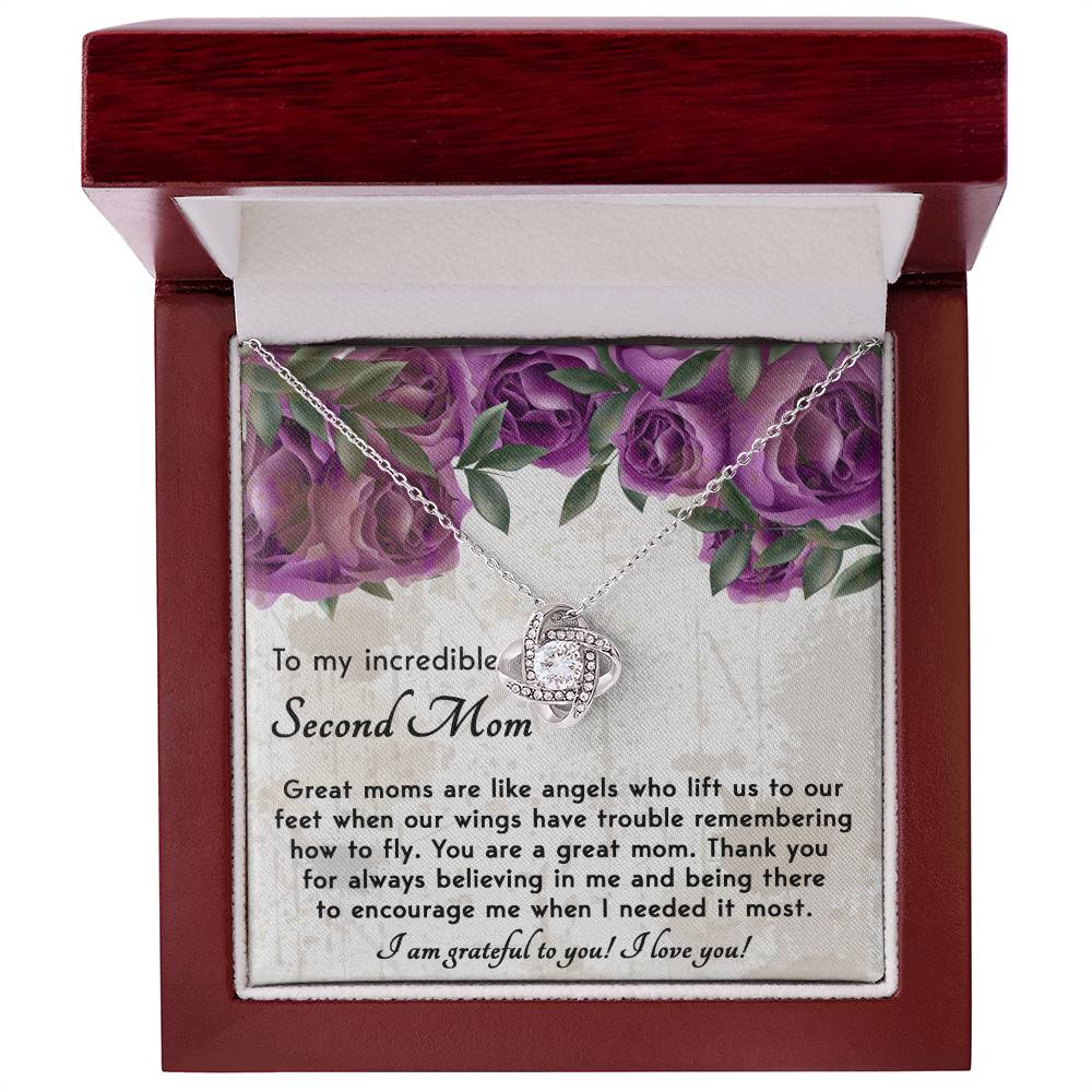 The "To Bonus Mom, Grateful For You - Love Knot Necklace" is showcased in a wooden box adorned with cubic zirconia crystals, accompanied by a heartfelt message expressing gratitude for support and encouragement to a "Bonus Mom," featuring an image of purple roses on the card.