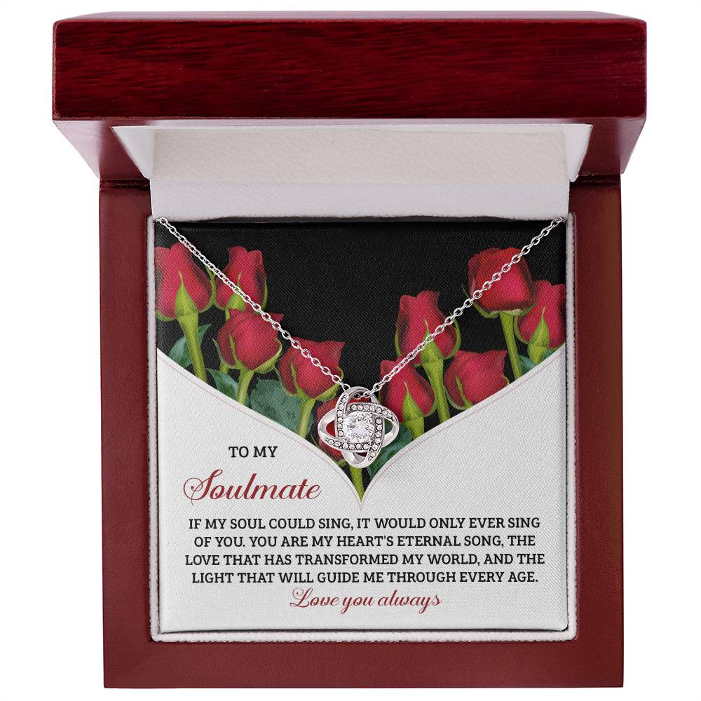 The Soulmate-Eternal Song Love Knot Necklace features a dazzling Cubic Zirconia with an exquisite gold finish. Presented in a decorative box against a red rose background, the message reads: "To my soulmate," followed by a poetic expression of love and devotion.