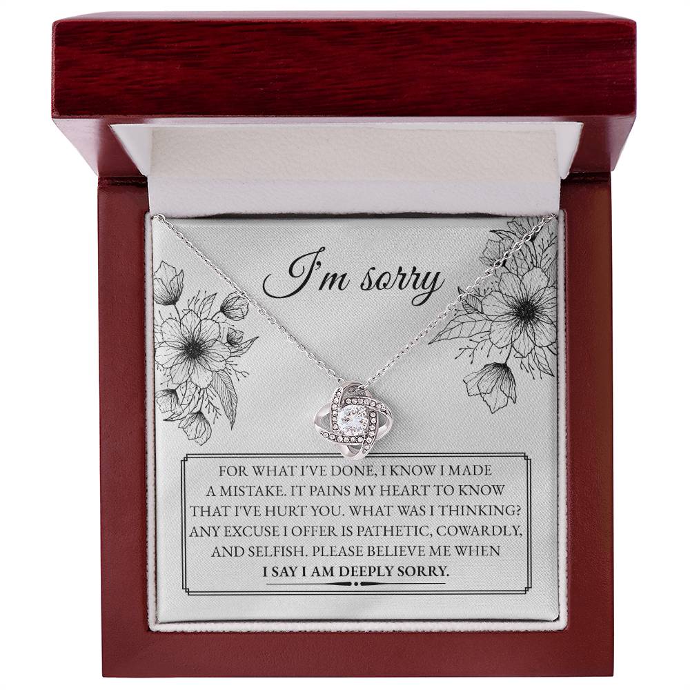 A "Sorry-Made A Mistake - Love Knot Necklace" features a box with a heartfelt apology message. The white gold finish and cubic zirconia crystals shimmer, as the text expresses deep regret and sorrow for causing hurt, describing the actions as pathetic, cowardly, and selfish, pleading for forgiveness.