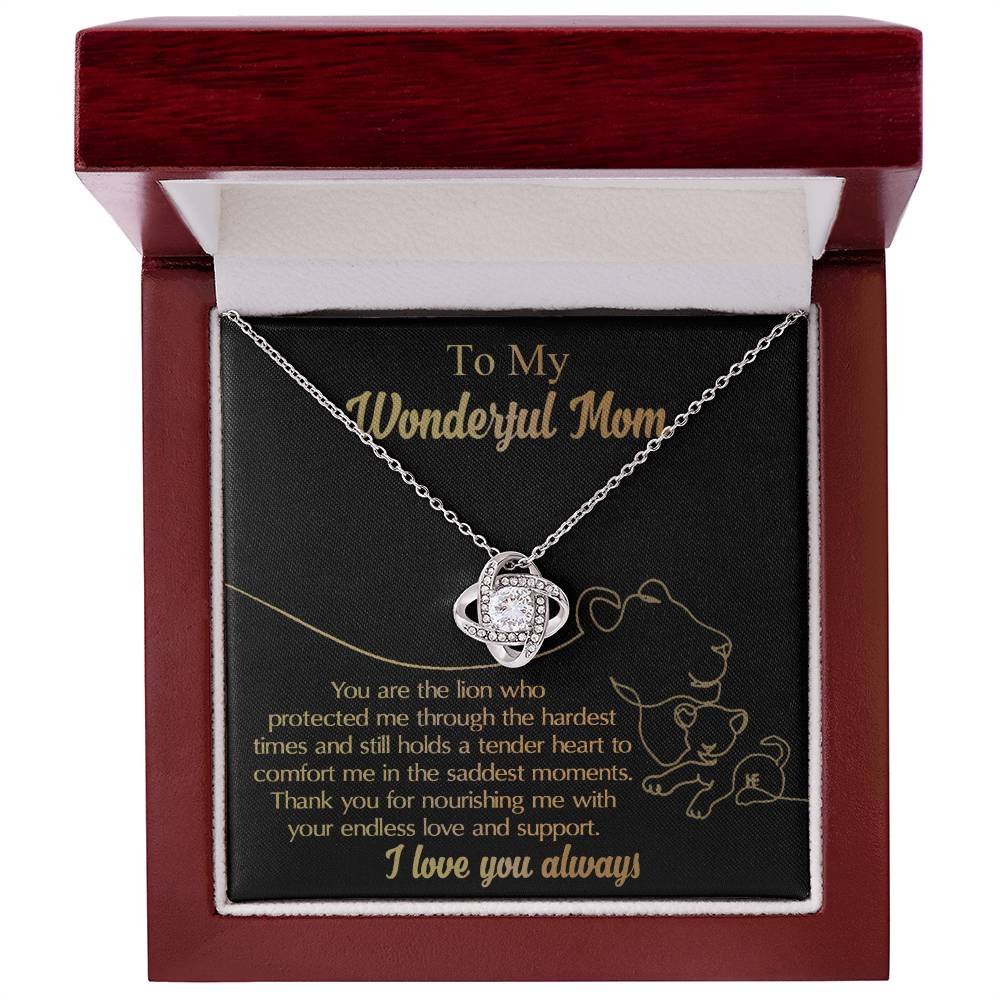The "To Mom, The Lion - Love Knot Necklace" features a round pendant made of white gold and adorned with cubic zirconia. It comes in a dark red box and includes a heartfelt message expressing gratitude and love for a mother, highlighting her support, protection, and nourishment.