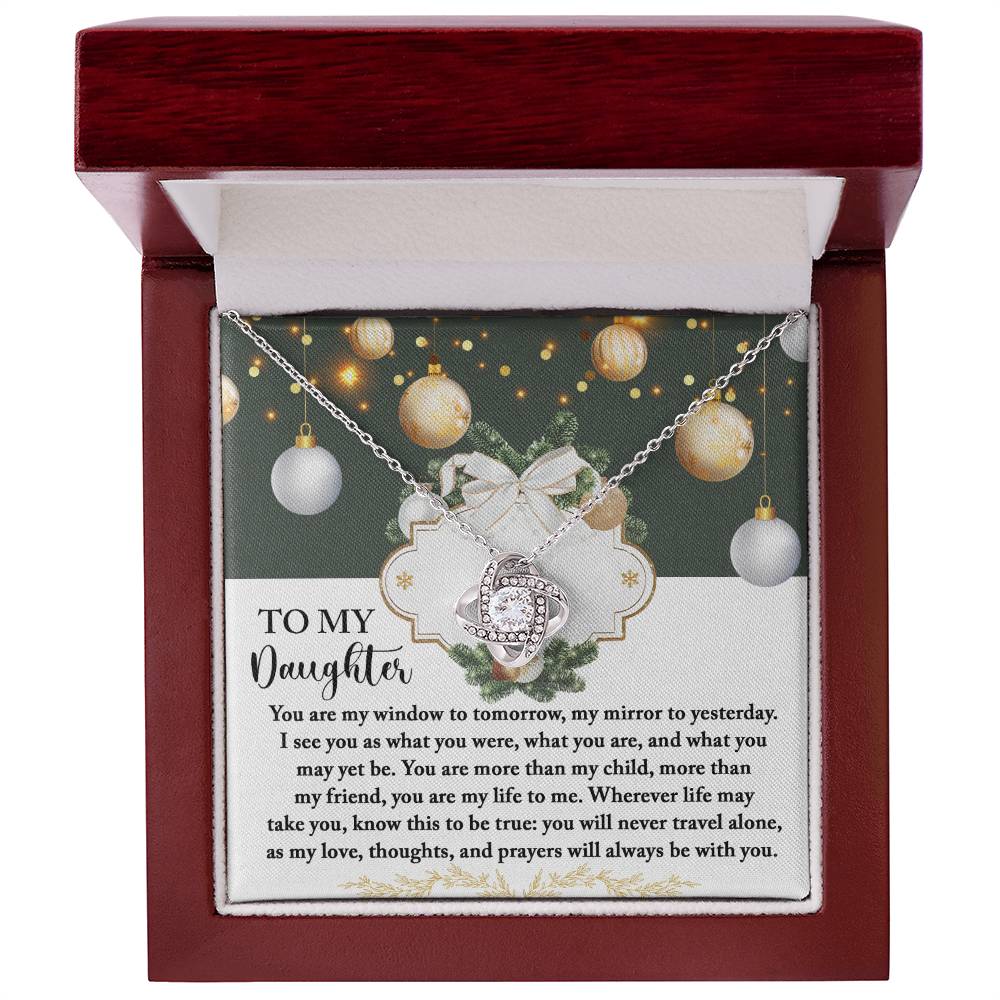 The Daughter-My Mirror - Love Knot Necklace, embellished with sparkling cubic zirconia crystals, is beautifully showcased in an open gift box. It comes with a heartfelt message specifically for a daughter, enhanced by decorative elements and warm lighting in the background for a more personalized touch.
