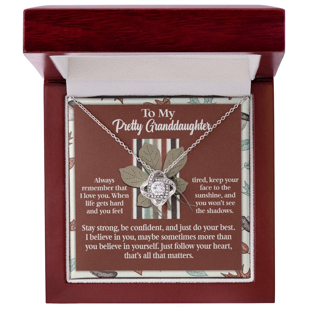 A Granddaughter-See The Shadows - Love Knot Necklace presented in a gift box, accompanied by a touching message about love, strength, and following her heart.
