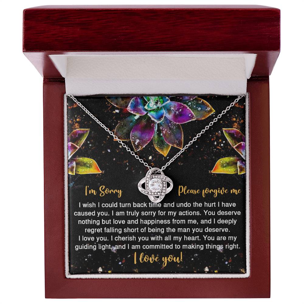 The Sorry-All My Heart - Love Knot Necklace features an interlocking heart pendant on a card with vibrant succulent graphics and the message: "I'm Sorry, Please forgive me. I love you." Adorned with sparkling cubic zirconia crystals, this necklace is available in a choice of white gold or yellow gold finish.