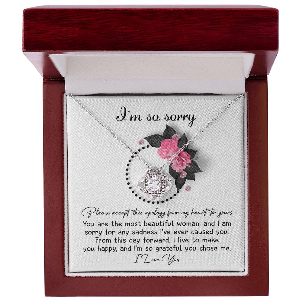 The Sorry-Make You Happy - Love Knot Necklace features a heart-shaped pendant adorned with cubic zirconia crystals, presented in a box decorated with pink flowers and the heartfelt text "I'm so sorry" at the top.