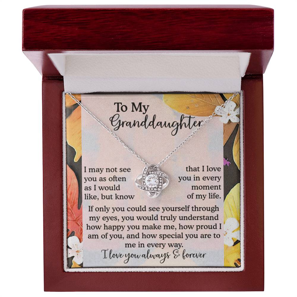The Granddaughter-In Every Way - Love Knot Necklace, featuring an interlocking heart pendant adorned with sparkling Cubic Zirconia, is elegantly displayed in a jewelry box with a heartfelt message for a granddaughter.