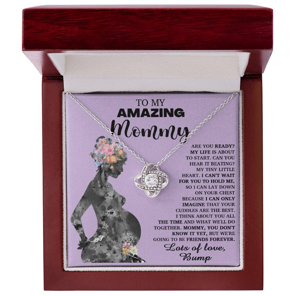 A "To Mom To Be, Tiny Little Heart - Love Knot Necklace" nestled in a box with a message titled "To My Amazing Mommy," featuring the silhouette of a pregnant woman. The heartfelt note from "Bump" expresses anticipation for birth and love, and the necklace is adorned with premium cubic zirconia crystals symbolizing an unbreakable bond.