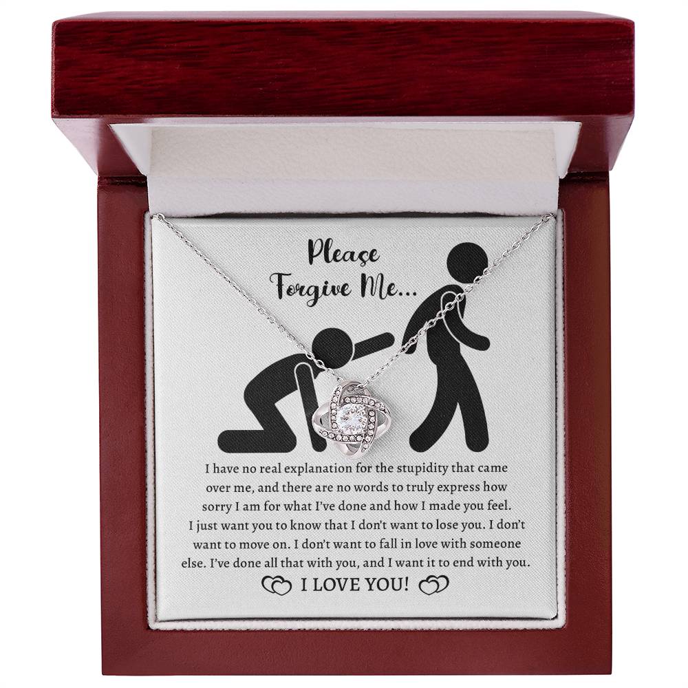 The Sorry-Made You Feel - Love Knot Necklace in 14k white gold and a card with the message "Please Forgive Me... I have no real explanation for the stupidity that came over me... I love you!" is shown. The necklace features intertwined hearts adorned with cubic zirconia crystals.