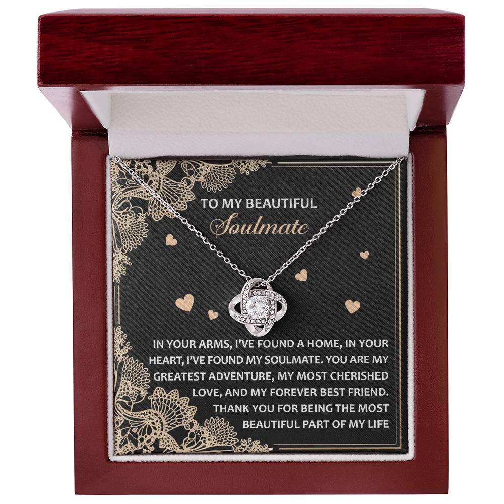 The Soulmate-Beautiful Part Love Knot Necklace, made of 14k white gold with cubic zirconia crystals, is presented in a box featuring a heartfelt message and a card with beautiful floral designs.