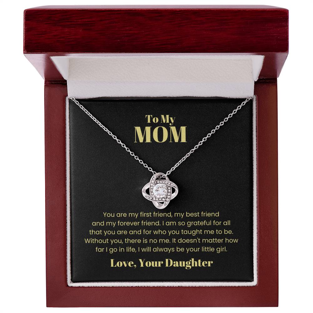 The To My Mom, You Are My First Friend - Love Knot Necklace is elegantly displayed in a gift box. Inside the lid, a heartwarming message reads, "To My MOM: You are my first friend... Love, Your Daughter." The necklace showcases dazzling cubic zirconia crystals and is available in either a white gold or yellow gold finish.