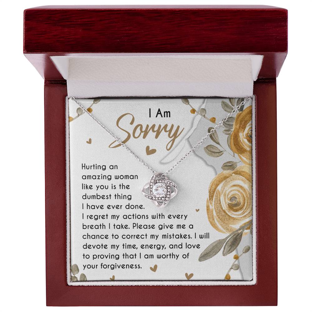 The Sorry-Amazing Woman - Love Knot Necklace, adorned with cubic zirconia crystals, rests in a jewelry box on a heartfelt note that reads, "I Am Sorry. Hurting an amazing woman like you is the dumbest thing I have ever done..." along with more apologetic text.