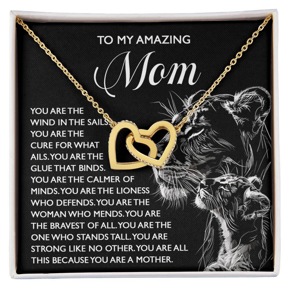 The Mom-The Cure - Interlocking Hearts Necklace, featuring cubic zirconia crystals, is displayed on a card with a lioness and cub illustration and the message "Mom," symbolizing strength, love, and elegance.
