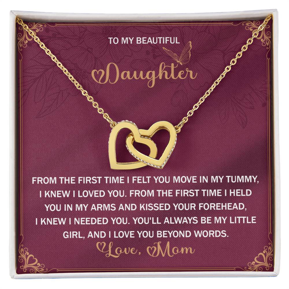The Daughter-Beyond Words - Interlocking Hearts Necklace is adorned with cubic zirconia crystals, features a rose gold finish on a red background, and includes an engraved message from a mother to her daughter expressing heartfelt love.