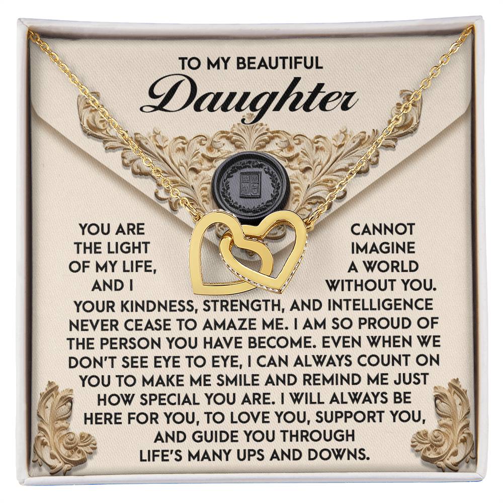 The Daughter-Amaze Me Interlocking Hearts Necklace, with a rose gold finish, elegantly rests on a decorative box. It features an engraved message of love and pride for your daughter and is adorned with shimmering cubic zirconia crystals, creating a timeless keepsake that captures your sentiments beautifully.