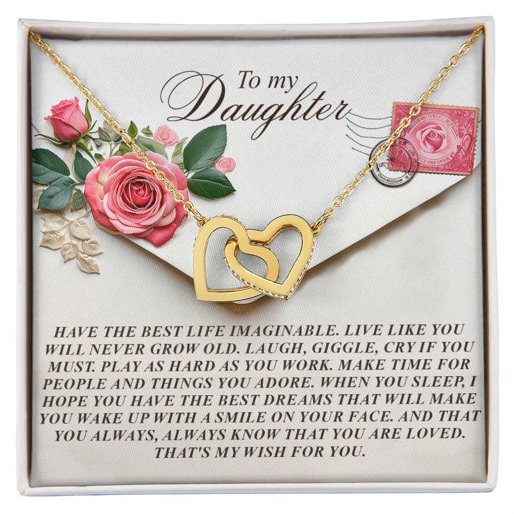 The Daughter-My Wish Interlocking Hearts Necklace in gold, adorned with cubic zirconia crystals, is beautifully presented in a gift box featuring roses and a heartfelt message encouraging a daughter to live joyfully and remember she is loved.