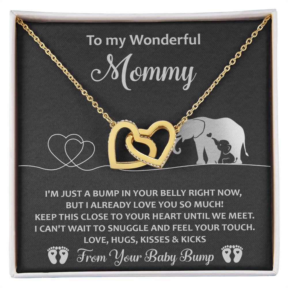 The "To Mama To Be, Until We Meet" necklace is a unique gift featuring interlocking gold hearts with cubic zirconia crystals. It's presented on a heartfelt card adorned with illustrated elephants and hearts, making it a special keepsake for an expecting mother.