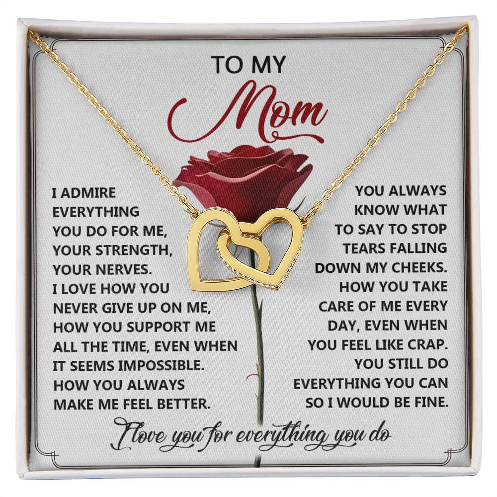 The Mom-Be Fine gift box includes an Interlocking Hearts necklace with gold hearts and cubic zirconia crystals. The lid features a red rose and a heartfelt message to appreciate mothers.
