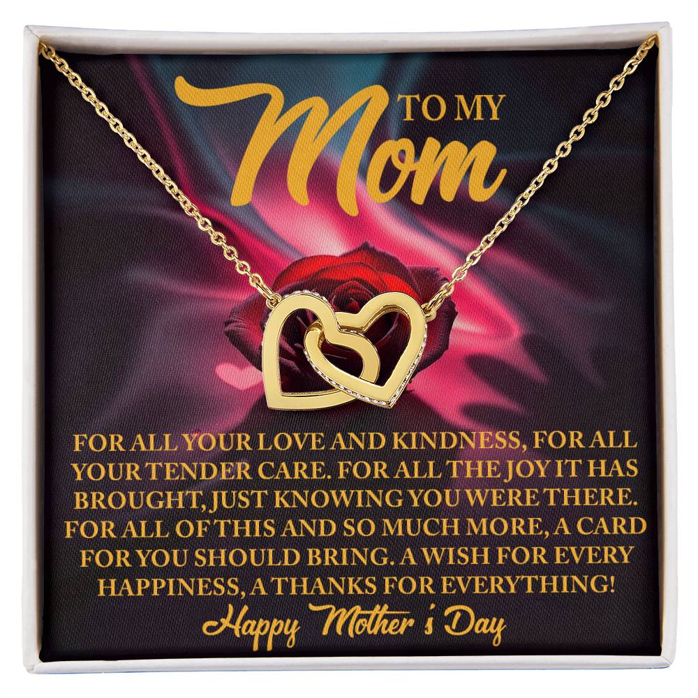The Mom-Tender Care - Interlocking Hearts Necklace, featuring dual heart pendants in 18k yellow gold finish, elegantly rests on a card with a rose backdrop and heartfelt message, expressing love and gratitude, ending with "Happy Mother's Day.