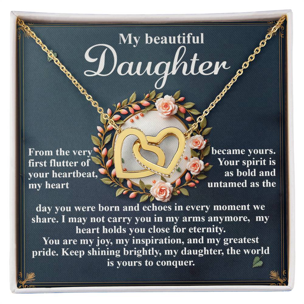 The Daughter-First Flutter jewelry gift box includes an Interlocking Hearts necklace with cubic zirconia, featuring two entwined hearts. "My beautiful Daughter" is inscribed on top, followed by a heartfelt message about love and inspiration. The necklace is elegantly framed by floral decorations.