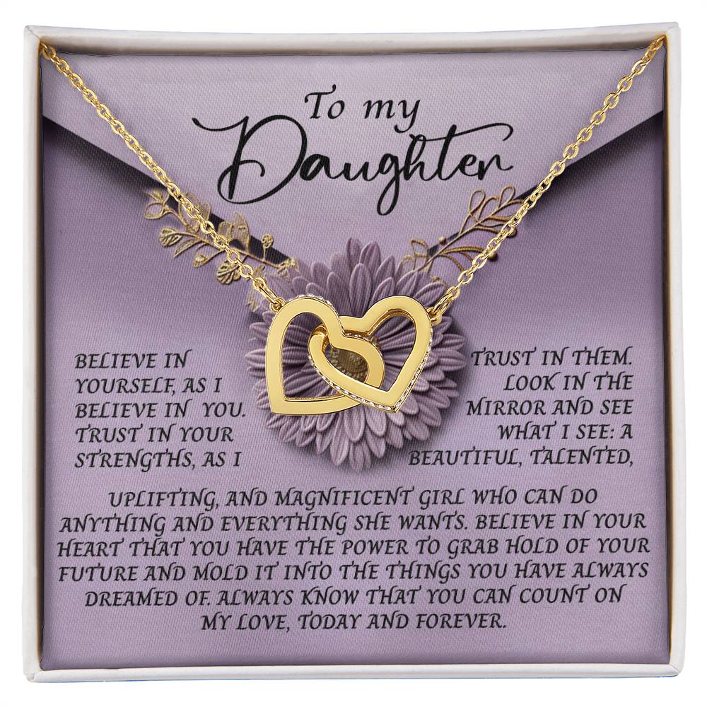 The Daughter-Magnificent Girl - Interlocking Hearts Necklace features two gold intertwined heart pendants with sparkling cubic zirconia crystals on a card titled "To my Daughter," adorned with floral designs and an inspiring message about self-belief, trust, and love.