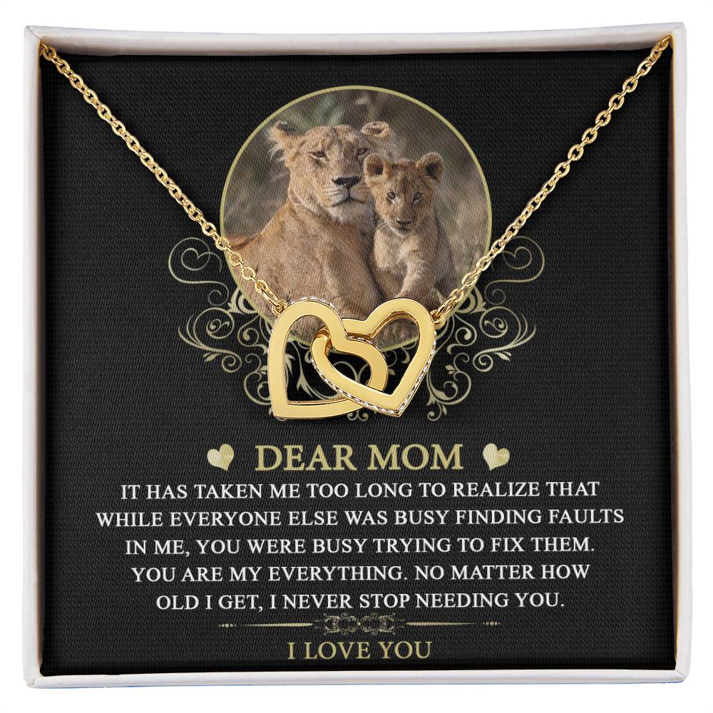 The "To Mom, My Everything - Interlocking Hearts Necklace" is adorned with cubic zirconia crystals and comes on a card featuring a lioness and cub with a heartfelt message conveying gratitude and love for a mother.