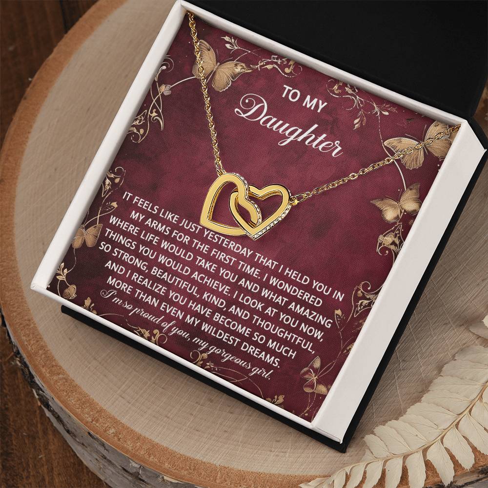 Gift box featuring the Daughter-Wildest Dreams - Interlocking Hearts Necklace on a red background, adorned with cubic zirconia crystals and a heartfelt message to a daughter.