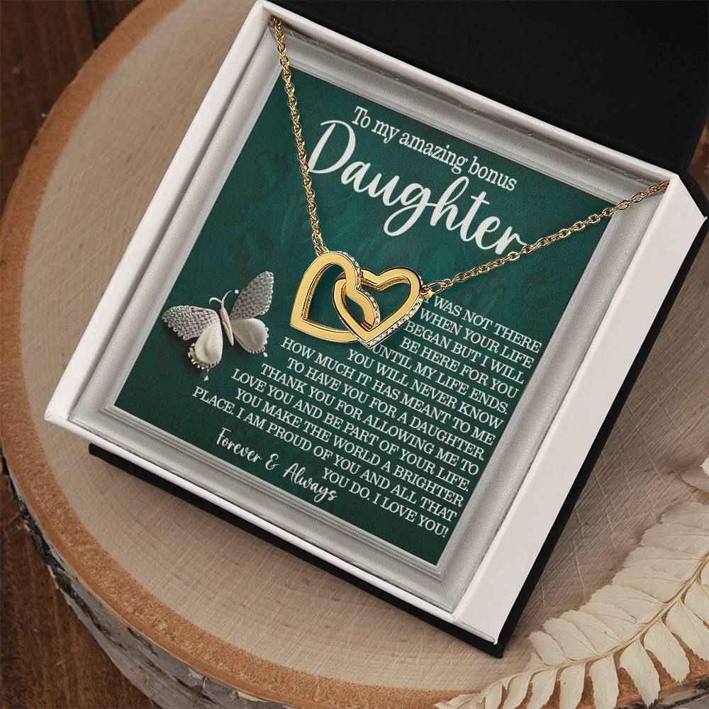 The Daughter-Your Life - Interlocking Hearts Necklace features a rose gold finish and cubic zirconia crystals, displayed on a sentimental message for a "bonus daughter," adorned with butterfly illustrations. It comes elegantly in a black box with white lining.