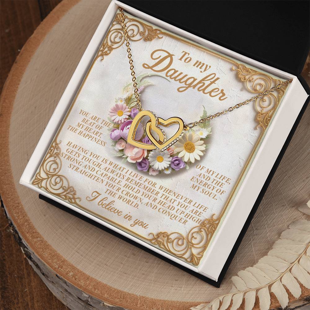 The Daughter-Heart Happiness necklace in rose gold finish features interlocking hearts with cubic zirconia crystals, elegantly presented on a decorative card with a heartfelt message for a daughter, enhanced by floral designs and ornate borders on a lace-accented wooden surface.