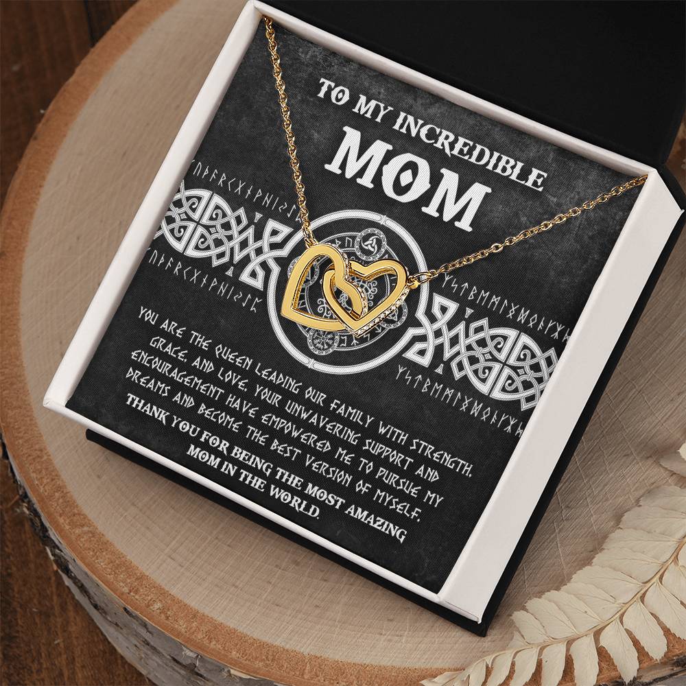 The "To Mom, The Queen 2 - Interlocking Hearts Necklace" gift box includes a necklace with cubic zirconia crystals and a heartfelt "To My Incredible Mom" message on the lid, all set on a wooden surface. It's the perfect personalized gift to make her feel truly cherished.