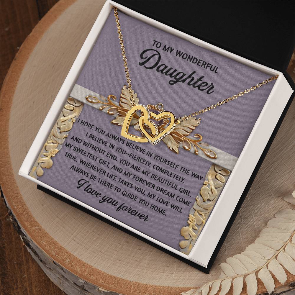 The Daughter-Guide You Home - Interlocking Hearts Necklace with rose gold finish and cubic zirconia crystals is displayed in an open box. Behind it, a sentimental message to a daughter features gold leaf accents, while the box rests elegantly on a wooden surface.