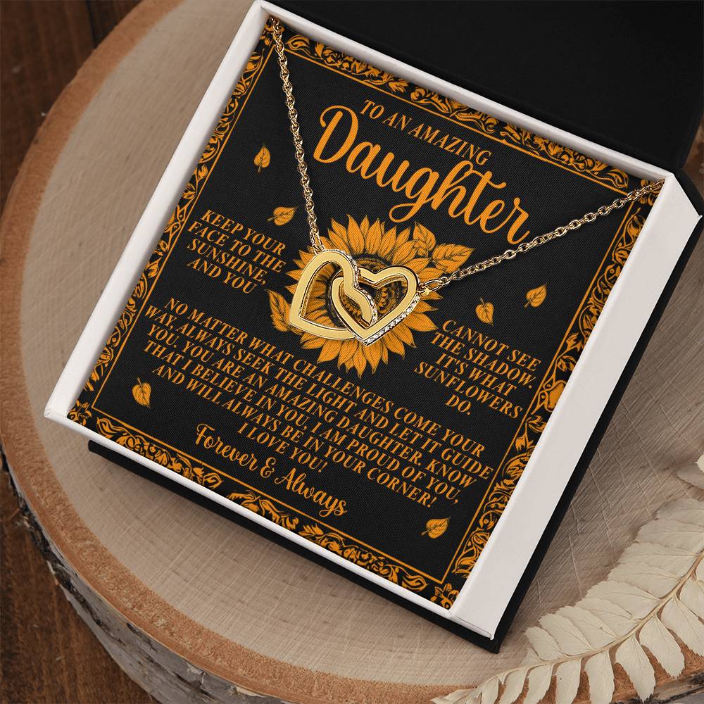 A perfect gift for her, the Daughter-Seek Light Interlocking Hearts Necklace features intertwined heart pendants with sparkling cubic zirconia crystals. It comes in a gift box, beautifully framed by sunflower and leaf designs on a wooden surface, with a heartfelt message for a daughter.