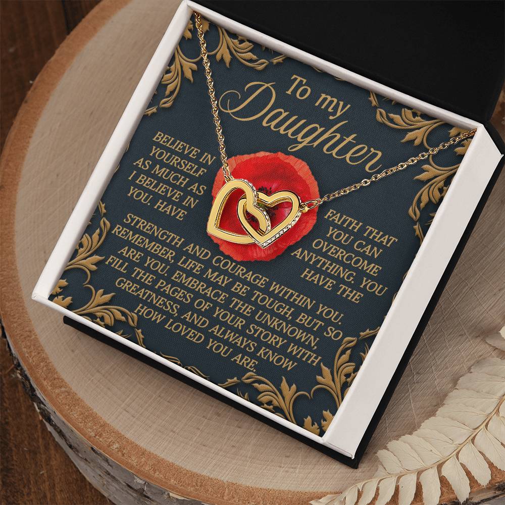The Daughter-With Greatness Interlocking Hearts Necklace features a rose gold finish and cubic zirconia crystals. It is displayed in a box with an inspirational message to a daughter in gold text and a red rose design, set against a wooden surface.