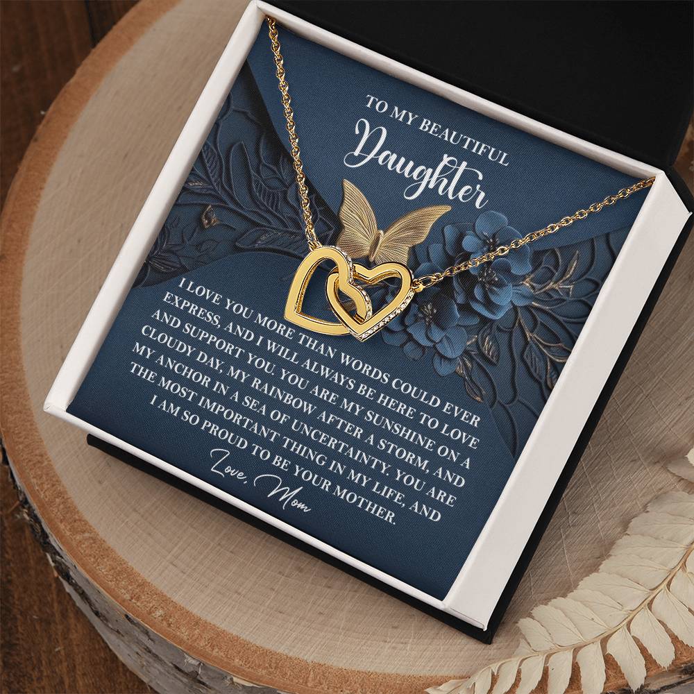 The Daughter-In My Life - Interlocking Hearts Necklace, featuring cubic zirconia crystals and a rose gold finish, is presented on a heartfelt message card from mother to daughter and elegantly nestled in a jewelry box.