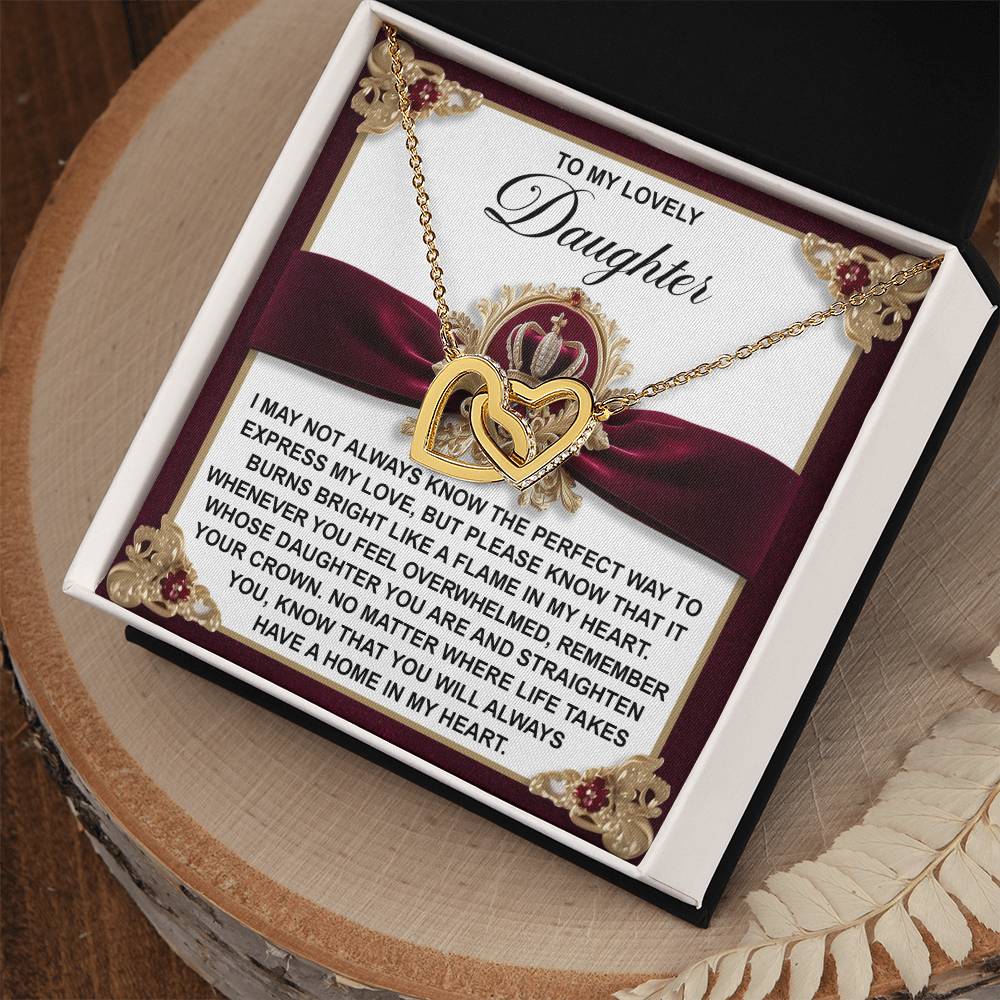 The Daughter-A Flame - Interlocking Hearts Necklace features a rose gold finish and cubic zirconia crystals. It comes in a decorative box with a burgundy bow, engraved with a message of love and pride for your cherished daughter.