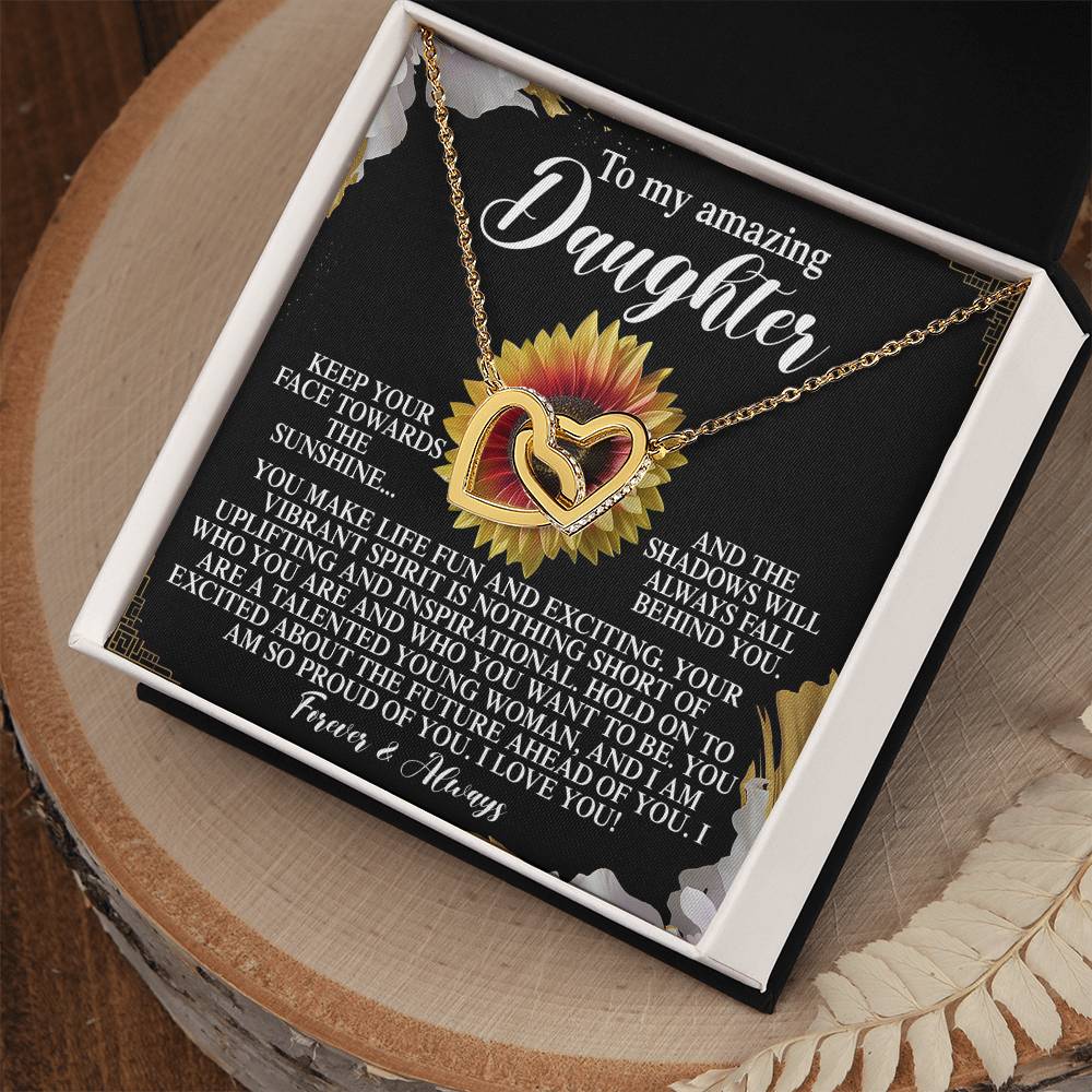 The Daughter-Vibrant Spirit - Interlocking Hearts Necklace, featuring a rose gold sunflower pendant with cubic zirconia crystals, sits beautifully in an open gift box. The lid reveals a heartfelt message to a daughter, expressing love, encouragement, and pride.